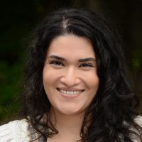 Headshot of Rebecca Beltran Benoit wearing a white top with a dark background